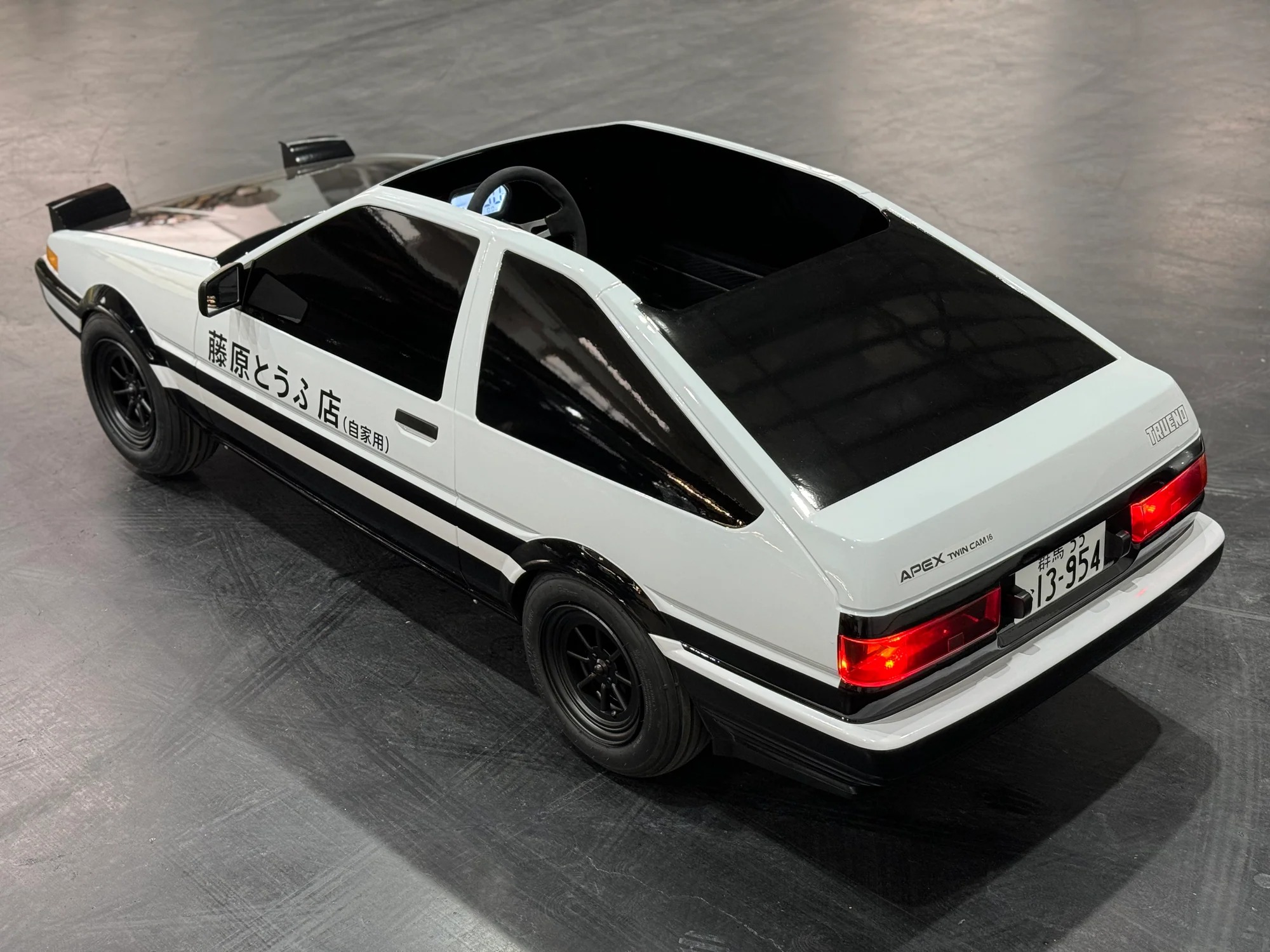 White and black Rennva Heritage AE86 Series electric kart in rear three-quarter view